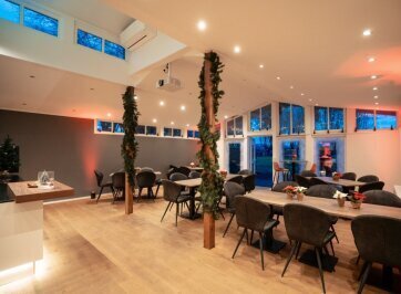 Beheizter Innenbereich mit gedeckten Tischen für das Abendessen bei der Weihnachtsfeier